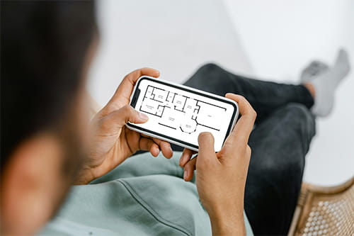 Man holding phone with floor plan on screen